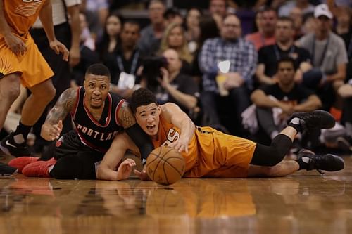 Damian Lillard #0 of the Portland Trail Blazers and Devin Booker #1 of the Phoenix Suns reach for a loose ball 