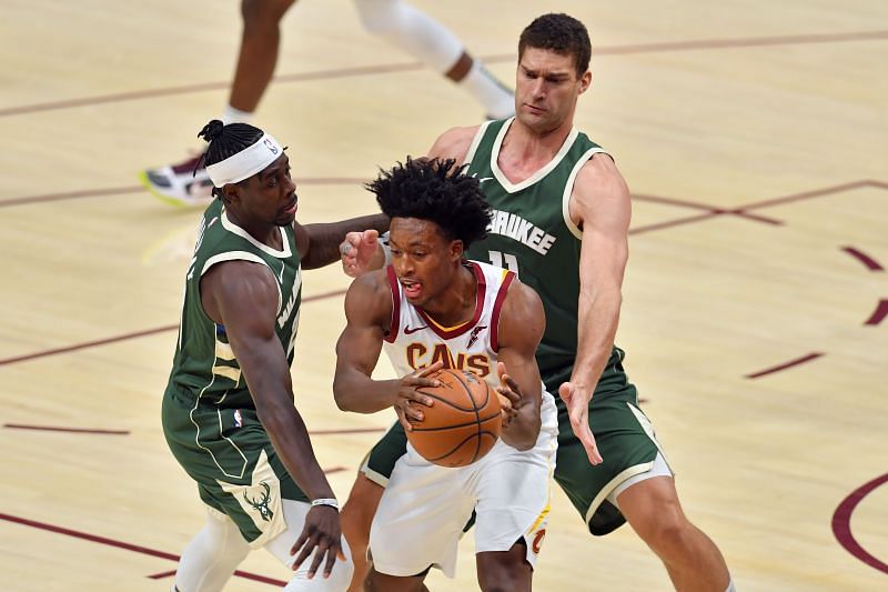 Collin Sexton #2 of the Cleveland Cavaliers tries to pass under pressure from Jrue Holiday #21 and Brook Lopez #11 of the Milwaukee Buck