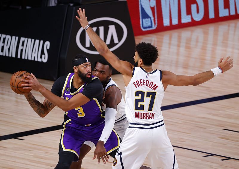 Anthony Davis of the Los Angeles Lakers drives the ball as Jamal Murray and Paul Millsap defend 