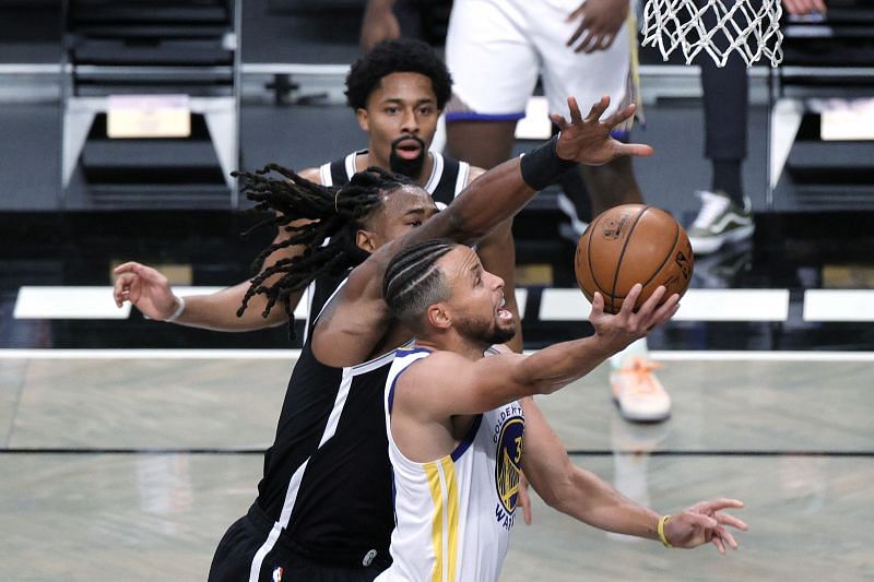 Stephen Curry of the Golden State Warriors attempts a layup against DeAndre Jordan and Spencer Dinwiddie of the Brooklyn Nets.