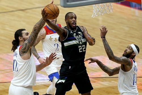 Khris Middleton of the Milwaukee Bucks goes up against Steven Adams and Brandon Ingram of the New Orleans Pelicans