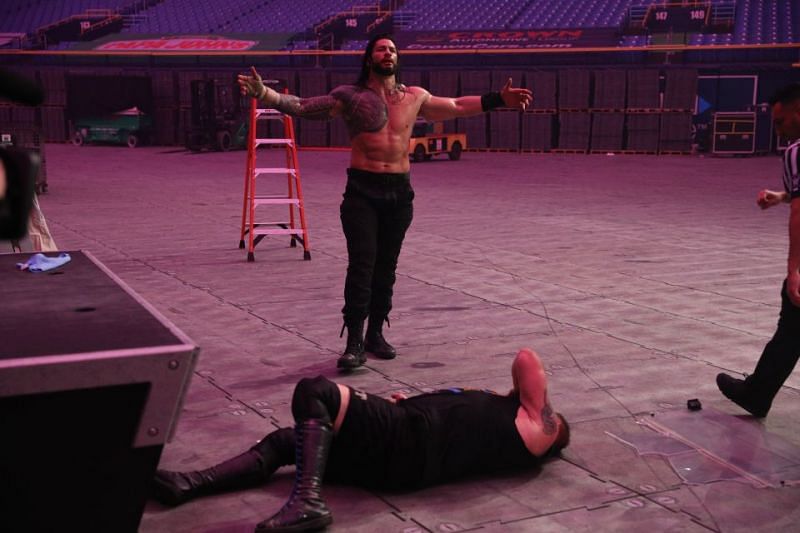 Roman Reigns stands over Kevin Owens during their match at WWE Royal Rumble