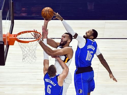 Rudy Gobert #27 of the Utah Jazz goes up for a shot against Kristaps Porzingis #6 and James Johnson #16 of the Dallas Mavericks