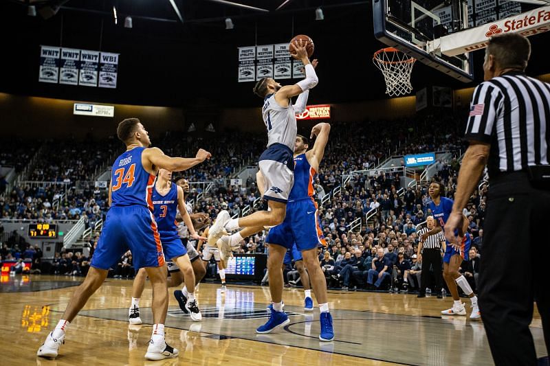 Nevada Wolf Pack player attempts a layup over the Boise State Broncos center.