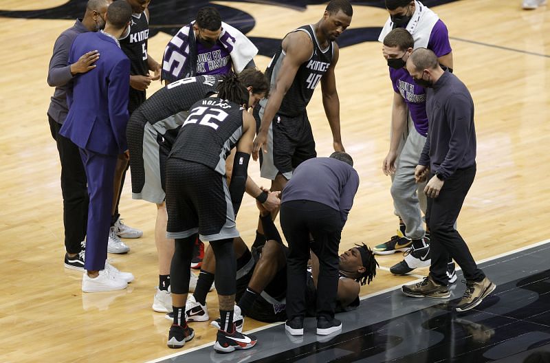 Buddy Hield (#24) of the Sacramento Kings is helped up by teammates and trainers after an injury in the Charlotte Hornets game.