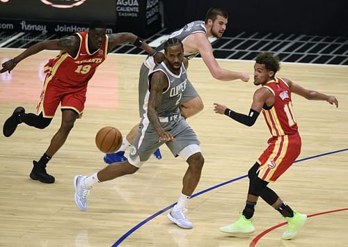 Kawhi Leonard (#2) passes between Trae Young (#11) and Tony Snell (#19)