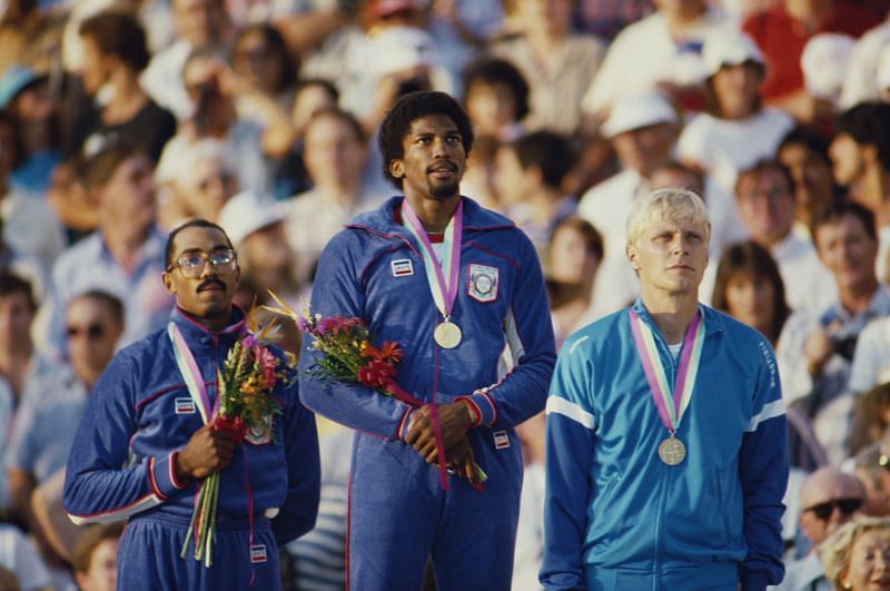 Roger Kingdom of the United States stands on the podium with his gold medal alongside silver medallist Greg Foster and bronze medallist Arto Bryggare in the Men&#039;s 110 metres Hurdles during the 1984 Summer Olympics