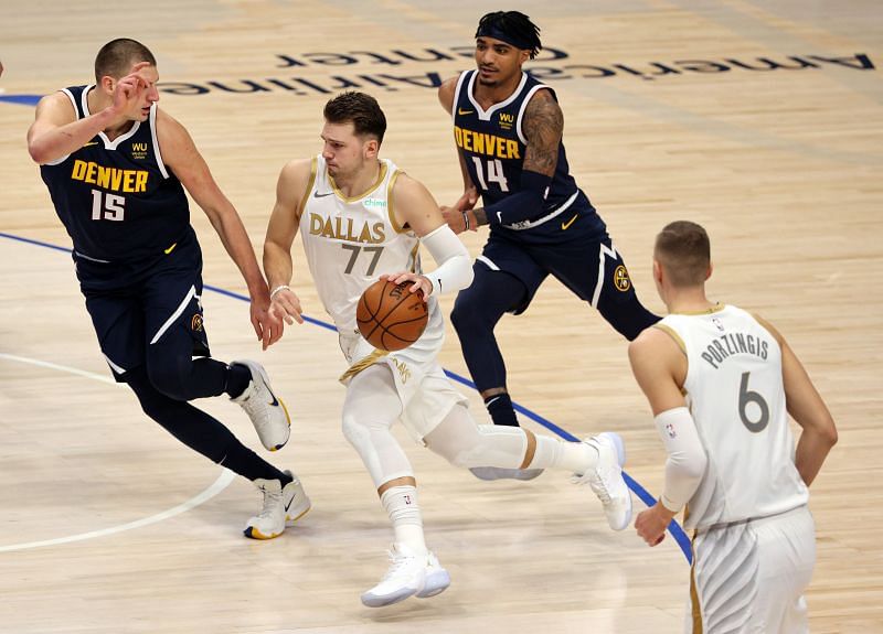 Luka Doncic #77 of the Dallas Mavericks dribbles the ball against Nikola Jokic #15 and Gary Harris #14 of the Denver Nuggets