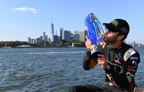 With the Manhattan skyline in the background, Jean-Eric Vergne kisses his championship trophy after the New York E-Prix. {Photo by FIA ABB Formula-E Handout/Getty Images,)