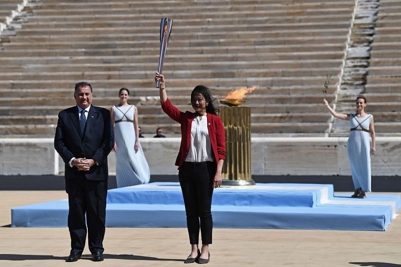 Greek Sports Minister and HOC President, Spyros Capralos hands over the Olympic torch to former Japanese swimmer Imoto Naoko during the Flame Handover Ceremony for the Tokyo 2020 Summer Olympics in March 2020, in Athens, Greece