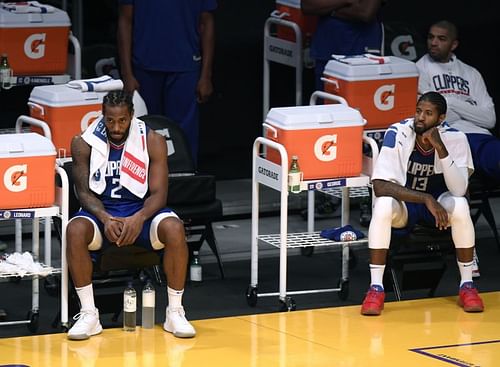 Kawhi Leonard #2 and Paul George #13 watch a game from the bench