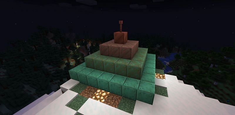 Shown: A progresively oxidizing monument overlooking a village (Image via Minecraft)