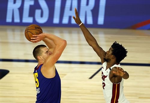 Nikola Jokic #15 shoots against Jimmy Butler #22.