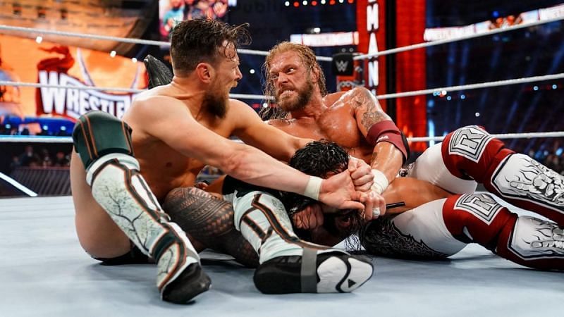 Daniel Bryan and Edge applying submission locks on Roman Reigns