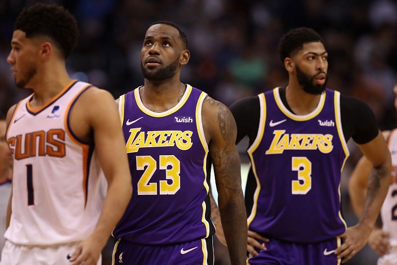 LeBron James #23 (C) stands between Devin Booker #1 and Anthony Davis #3