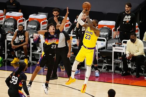 LeBron James (#23) attempts a three-point shot over Cameron Johnson (#23).