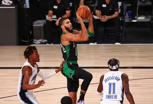 Jayson Tatum #0 of the Boston Celtics shoots against Wes Iwundu #25 and James Ennis III #11 of the Orlando Magic.