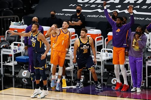 Devin Booker (#1) of the Phoenix Suns watches his three-point shot over Rudy Gobert (#27) and Georges Niang (#31) of Utah Jazz.