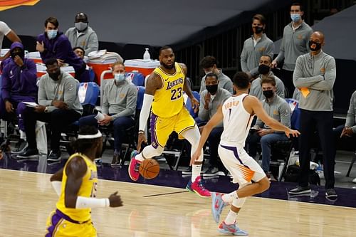 LeBron James #23 of the Los Angeles Lakers handles the ball against Devin Booker #1 of the Phoenix Suns.