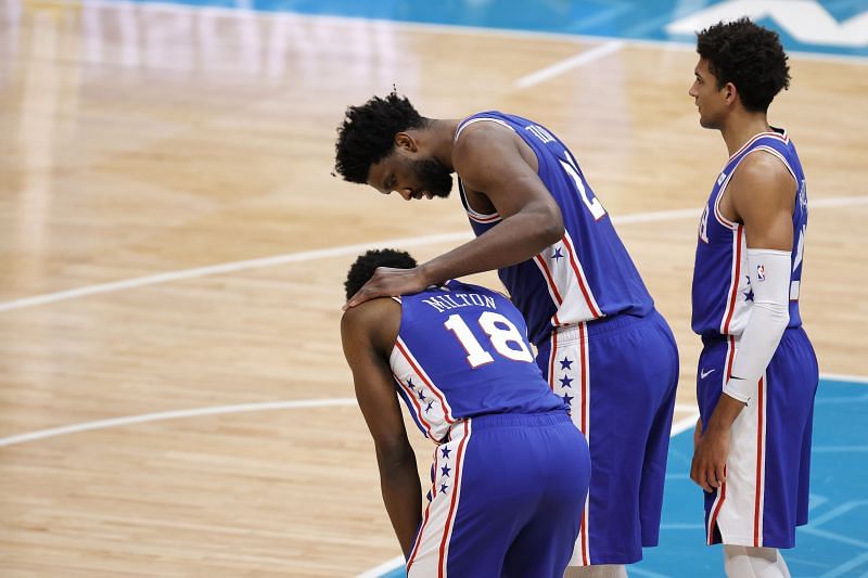Shake Milton #18 is is checked on by teammate Joel Embiid #21 following an injury.