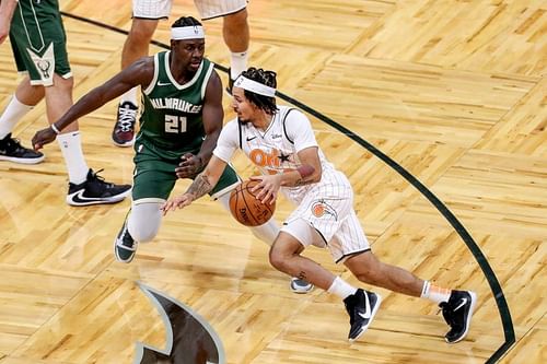 Cole Anthony drives to the basket while being defended by Jrue Holiday