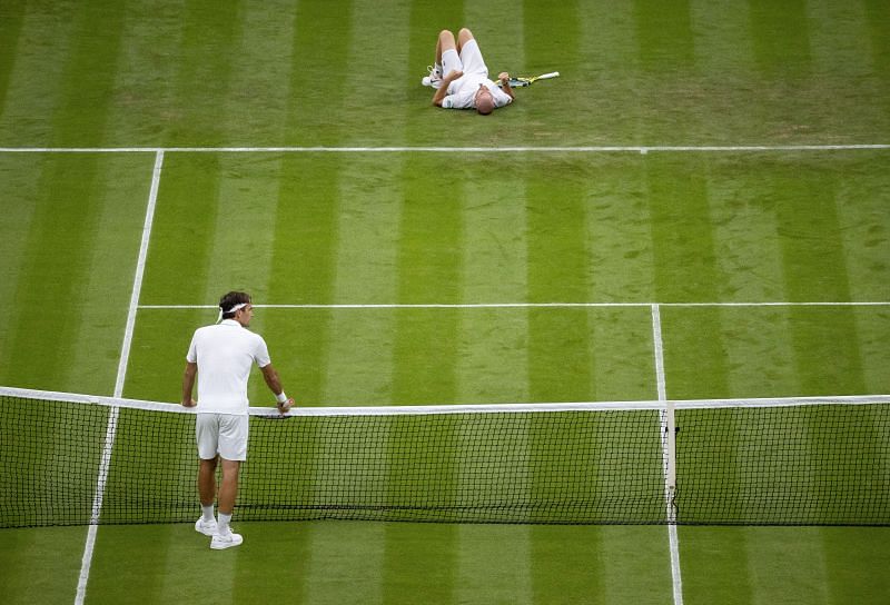 Roger Federer waits at the net as Adrian Mannarino takes a tumble