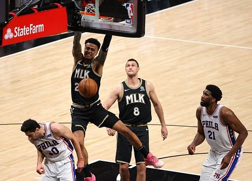 John Collins #20 of the Atlanta Hawks dunks against Furkan Korkmaz #30 and Joel Embiid #21