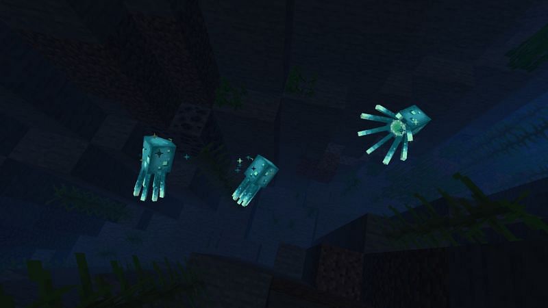 Three glow squids in a deep ravine (Image via Minecraft)