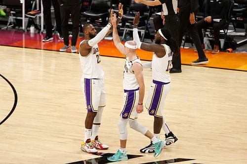 LeBron James #23 high fives Alex Caruso #4 and Montrezl Harrell #15.