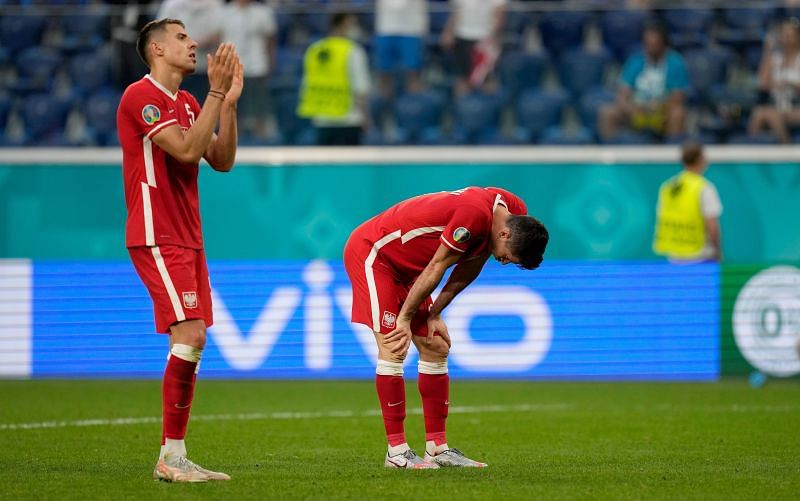 Lewandowski (right) is dejected after Poland crashed out of Euro 2020 despite his brace against Sweden