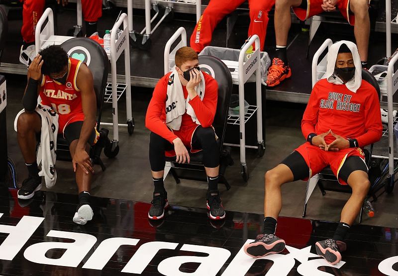 Solomon Hill (#18), Kevin Huerter (#3) and John Collins (#20) of the Atlanta Hawks look on from the bench.