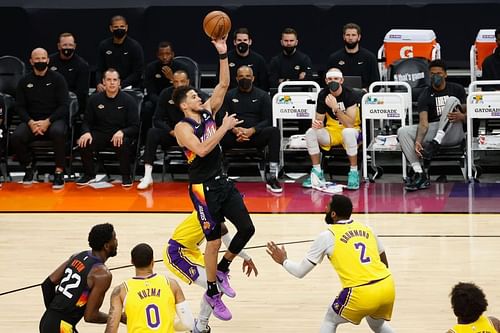 Devin Booker #1 puts up a shot over Andre Drummond #2