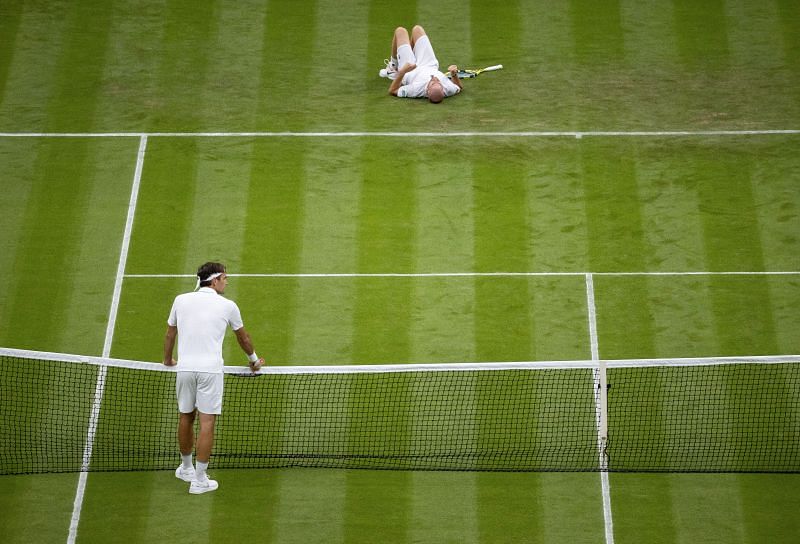 Adrian Mannarino after his fall as Roger Federer looks on