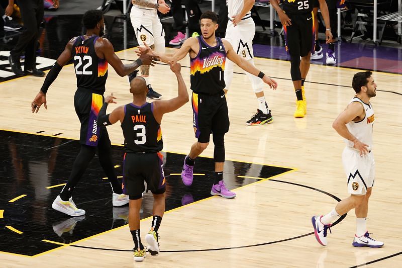 Devin Booker #1 high-fives Deandre Ayton #22 and Chris Paul #3 after scoring against the Denver Nuggets