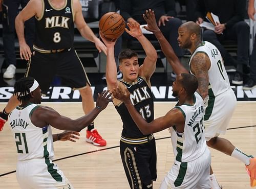 Bogdan Bogdanovic #13 is defended by Jrue Holiday #21 and Khris Middleton #22