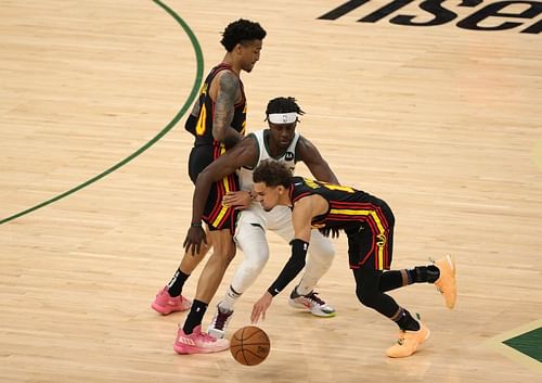 Trae Young and John Collins of the Atlanta Hawks in action against Jrue Holiday of the Milwaukee Bucks