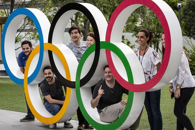People have their photographs taken next to the Olympic Rings in Tokyo