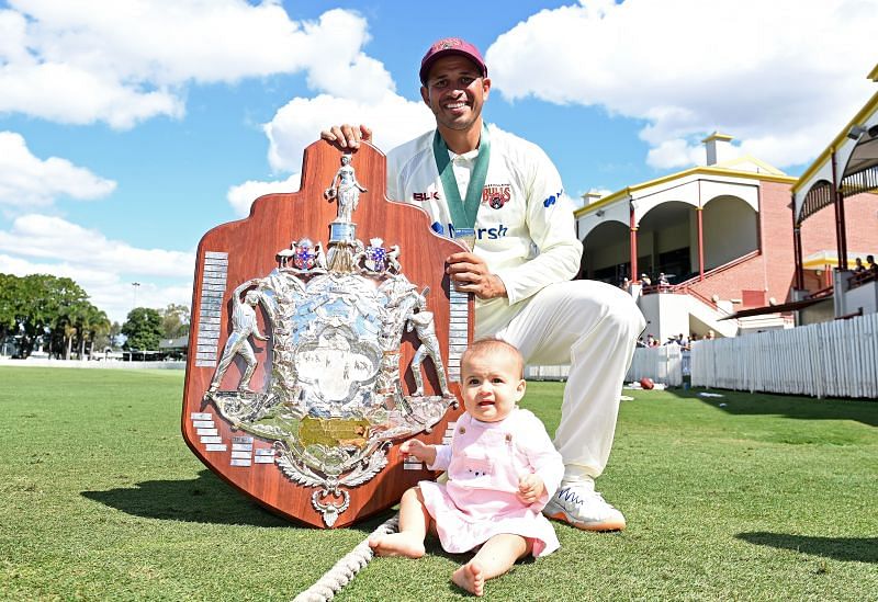 Usman Khawaja and his daughter pose with the Sheffield Shield trophy