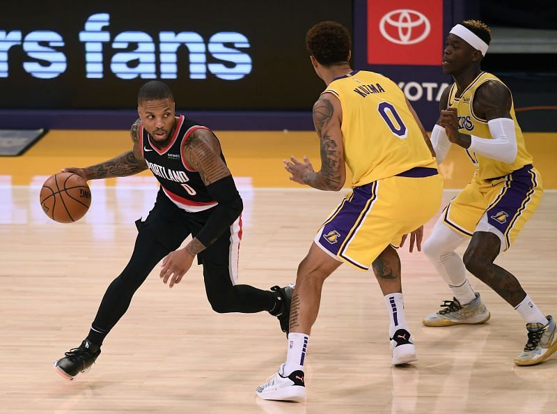 Damian Lillard #0 dribbles away from a double team by Kyle Kuzma #0 and Dennis Schroder #17.