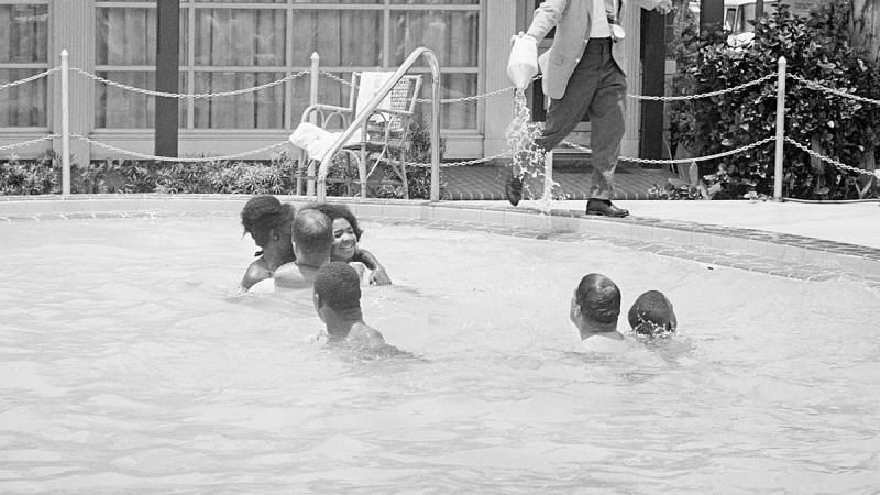 A picture of black people enjoying swimming and a hotel manager in the US pouring acid into the pool (1964)