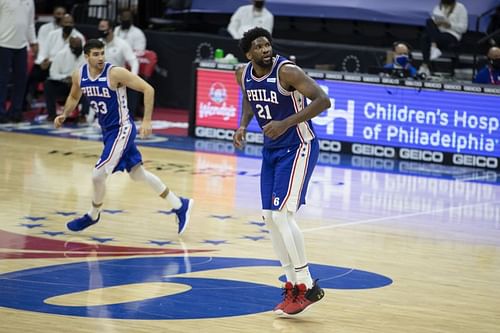 Joel Embiid #21 and Dakota Mathias #33 in action