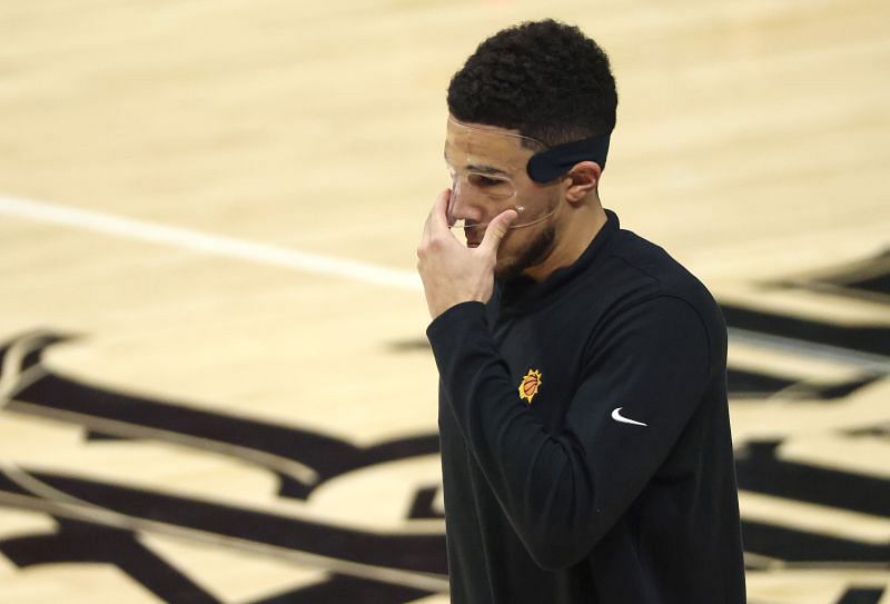 Devin Booker adjusts his face mask