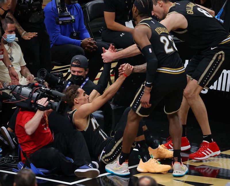 Trae Young #11 of the Atlanta Hawks is helped up by teammates Danilo Gallinari #8 and Cam Reddish #22.