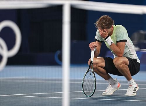 Alexander Zverev sinks to the turf after downing Novak Djokovic to reach the gold-medal match at the Tokyo Olympics.