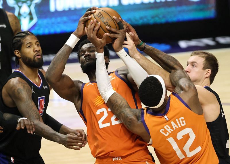 Deandre Ayton #22 and Torrey Craig #12 fight for a rebound against Paul George #13 and Luke Kennard #5