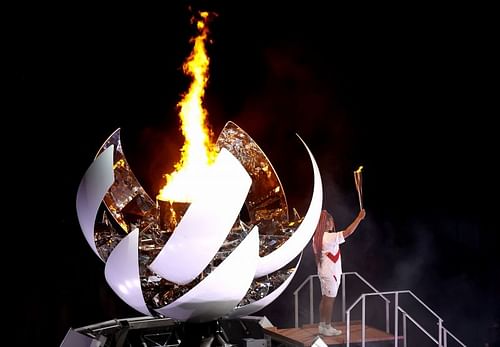 Naomi Osaka holds up the torch after lighting the cauldron