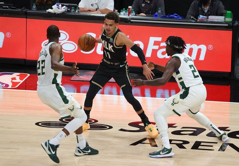 Trae Young #11 is defended by Khris Middleton #22 and Jrue Holiday #21