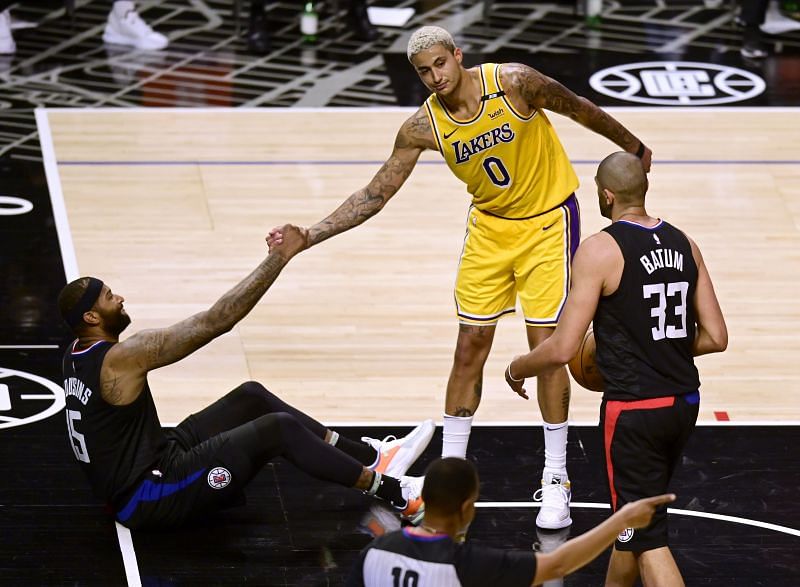 Kyle Kuzma #0 of the Los Angeles Lakers reacts as he helps up DeMarcus Cousins #15 of the LA Clippers