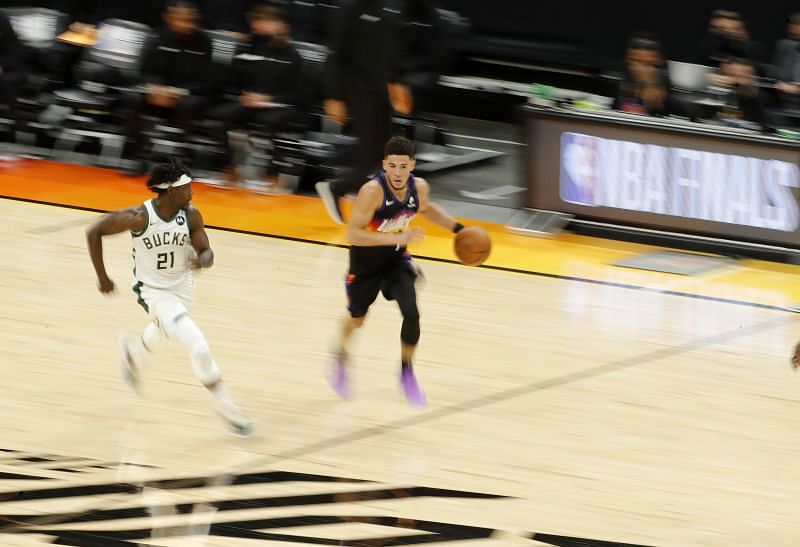 Devin Booker #1 brings the ball up court against Jrue Holiday #21