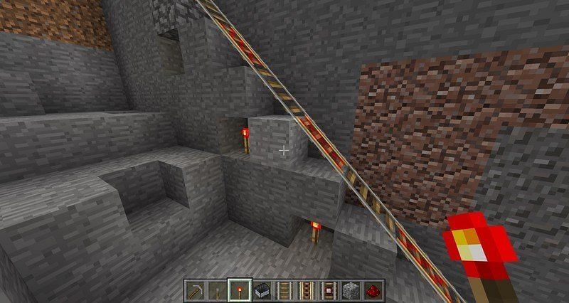 A Minecraft player powering their rails with redstone torches under the block (Image via windowscentral)